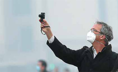 A visitor takes a photo at Tian'anmen Square on Feb 25, when Beijing issued an orange alert. [Zou Hong / China Daily]