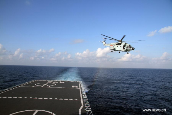 A helicopter takes off from the Chinese naval vessel Jianggangshan to carry out search at the possible crash site of missing Malaysia Airlines flight MH370, March 13, 2014.  (Xinhua/Gan Jun)