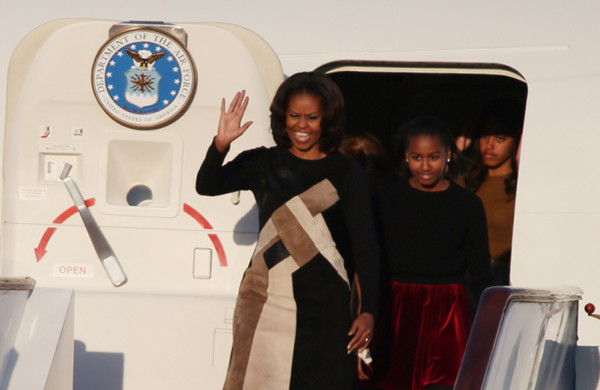 US first lady Michelle Obama waves as she walks off a plane at Beijing Capital International Airport on Thursday, followed by her daughters Malia and Sasha. Mrs Obama is kicking off a weeklong, three-city tour of China that analysts said will further advance relations between Beijing and Washington. [Photo by Wang Jing/chinadaily.com.cn]