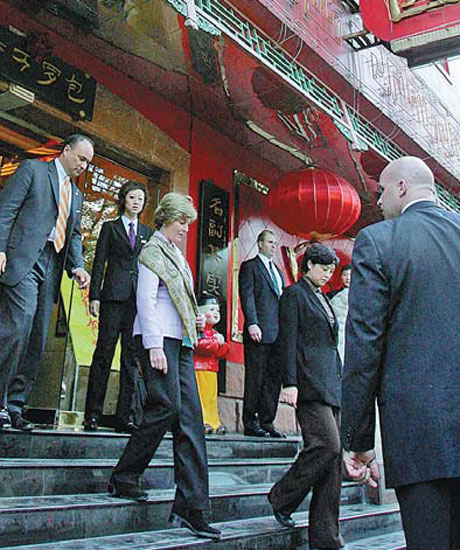 Former first lady Laura Bush (center) walks out of the Tianjin Baijiaoyuan restaurant where she ate lunch in Beijing in November 2005. Provided to China Daily