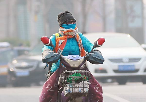 A mask-wearing resident rides an electric bike on the Dongzhimen Overpass in Beijing on Monday. The air quality index in the capital reached 320, indicating severe pollution. ZOU HONG / CHINA DAILY