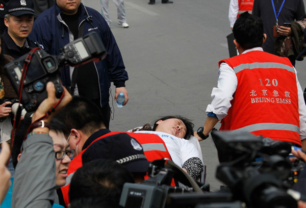 A relative who fainted at the Malaysian Embassy on Tuesday is taken away on a stretcher. KUANG LINHUA / CHINA DAILY 