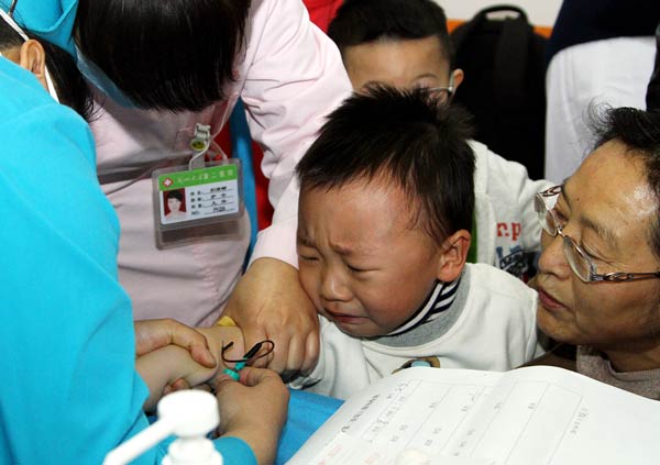 Nurses draw blood for a test on Wednesday from a child enrolled at Litian Kindergarten in Lanzhou, Gansu province. The school is under investigation after the head of the school admitted that students were given prescribed anti-viral drugs. DING KAI / FOR CHINA DAILY
