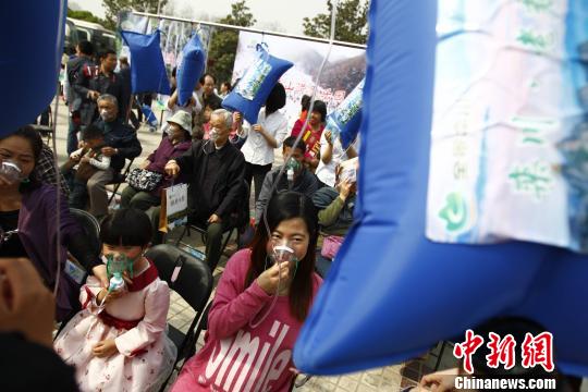 Locals line up for a lungful from one of the 20 masks hooked up to pillow-sized bags filled with certified air from the mountain area on March 29, 2014. [Photo: CHina News Service]