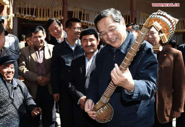 Yu Zhengsheng (1st R, front), a member of the Standing Committee of the Political Bureau of the Communist Party of China Central Committee and chairman of the Chinese People's Political Consultative Conference National Committee, plays Rawap, a traditional Uygur instrument, while visiting an employment promotion project in Kashgar, northwest China's Xinjiang Uygur Autonomous Region, March 26, 2014. Yu made a study tour of Xinjiang from March 26 to 30. (Xinhua/Liu Jiansheng)