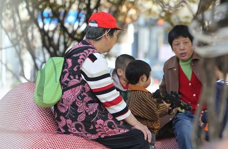 Grandmothers take their grandchildren to a neighborhood public square for a morning stroll in Shanghai. According to a recent survey, nearly half grandparents regard caring grandchildren a duty and are reluctant to do it. (Photo source: Shanghai Daily)