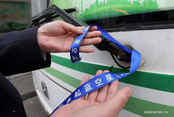 A bus driver shows the blue ribbon tied on the bus marking the World Autism Awareness Day in Shanghai, east China, April 2, 2014. Over 30,000 public transport vehicles were put on blue ribbons to call for public care for autistic children in Shanghai on Wednesday. [Photo: Xinhua/Ding Ting]