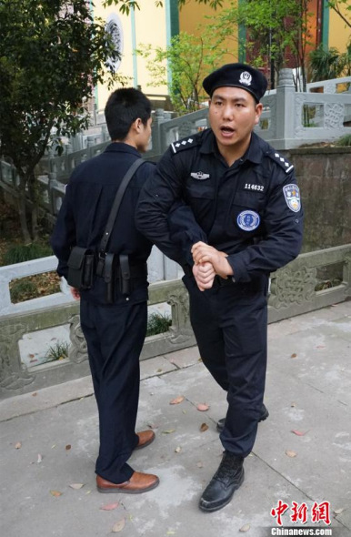 An anti-terrorist policeman teaches a security guard skills against violence and terrorist attacks at the Lingyin Temple in Hangzhou,  Zhejiang province, April 3, 2014. (Photo/CNS)