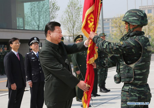 Chinese President Xi Jinping (L, front), who is also chairman of the Central Military Commission (CMC), presents a new flag to the Falcon Commando Unit, an elite police counter-terror brigade, at the Special Police Academy of the Chinese People's Armed Police Force, in Beijing, capital of China, April 9, 2014. (Xinhua/Li Gang)