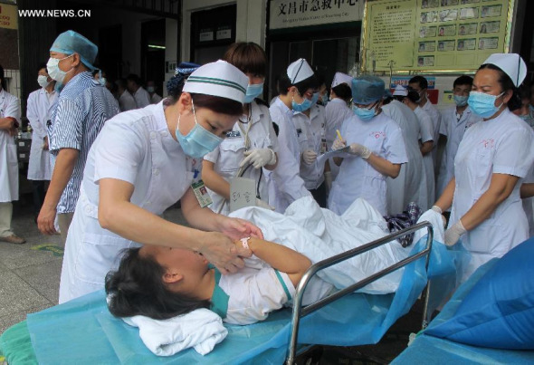 Medical workers give treatment to injured passengers of a bus overturn accident in Wenchang City, south China's Hainan Province, April 10, 2014. Eight pupils died and 32 were injured when their bus for spring outing overturned in Chengmai County of Hainan Province on Thursday morning. All the injured have been sent to hospital and the cause of the accident is under investigation. (Xinhua/Chen Fei)