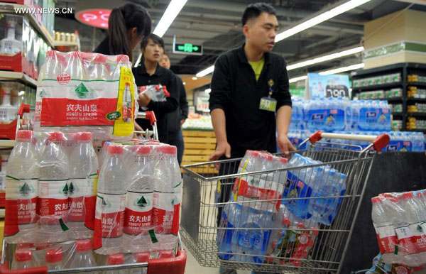 Citizens load bottles of water at a supermarket in Lanzhou, capital of northwest China's Gansu Province, April 11, 2014. Tap water in downtown Lanzhou has been found to contain excessive levels of benzene, provincial authorities said on Friday. [Photo/Xinhua]