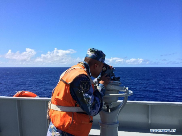 A sailor aboard Chinese navy's amphibious landing vessel Jinggangshan scans the ocean in search for the missing Malaysia Airlines flight MH370, in southern Indian Ocean, on April 13, 2014.  (Xinhua/Bai Ruixue)