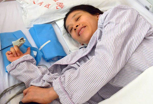 Paralyzed former gymnastics champion Sang Lan lies in bed after giving birth to a baby boy by cesarean section on Monday in Beijing. Sang fell during warm-ups at the Goodwill Games in 1998 in the US, leaving her paralyzed from the mid-chest down. Tang Shizeng / Xinhua News Agency
