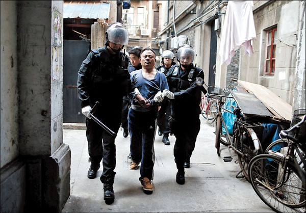 Yan is led away by police in a lane on Xiangyang Road N. yesterday. — Yang Yi 