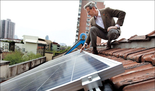 Canadian Jason Inch checks the solar panels in Xuhui District yesterday. The six solar panels he installed on the roof of his office can support 70- plus 10-watt LED bulbs in the six-storey building. He sells the surplus power to the local power grid. — Xinhua 