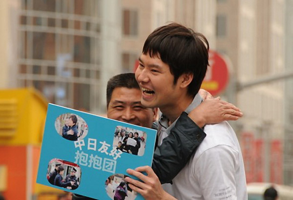 A Japanese student hugs a Chinese pedestrian on Wangfujing Street in Beijing on April 10, while holding a sign saying Hug to promote friendship between China and Japan. Provided to China Daily