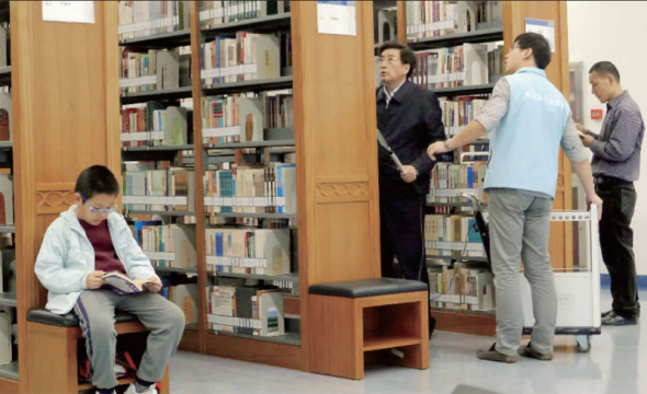 The Communist Party Chief in Beijing Guo Jinlong is seen arranging returned books at Capital Library in Beijing on Saturday, April 19, 2014. [Photo/Beijing Morning Post]