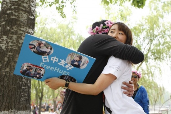 A Japanese exchange student at Peking University offers hugs to passers-by in Beijing. [Photo / hi.people.cn]