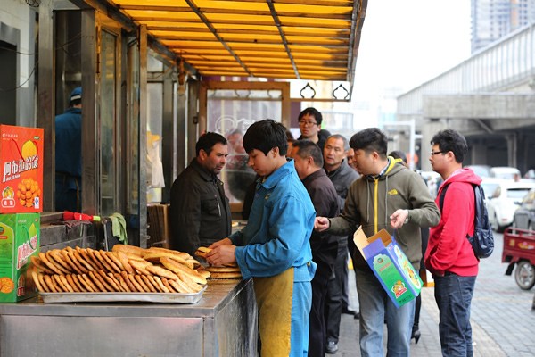 A baker works naan bread at a branch of Abula's Naan in Urumqi, Xinjiang Uygure autonomous region. [Chen Yan / For China Daily]