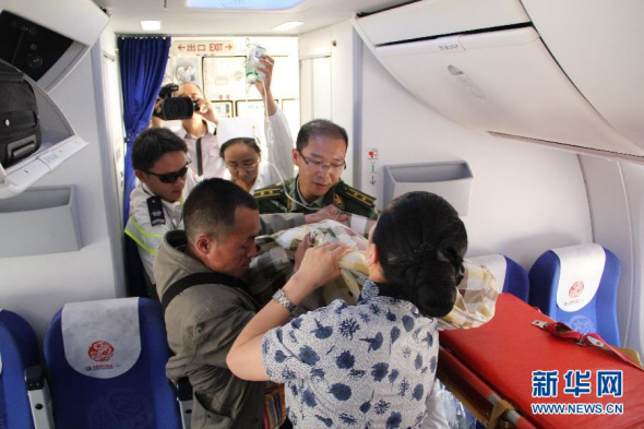 Pu Yanfang on a stretcher is carried onto a plane of China Eastern Airlines on April 23, 2014. [Photo: Xinhua]