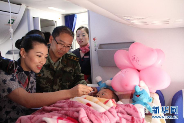 A flight attendant feeds Pu on the plane on April 23, 2014, with children's toys and balloons given by the crew around her. [Photo: Xinhua]