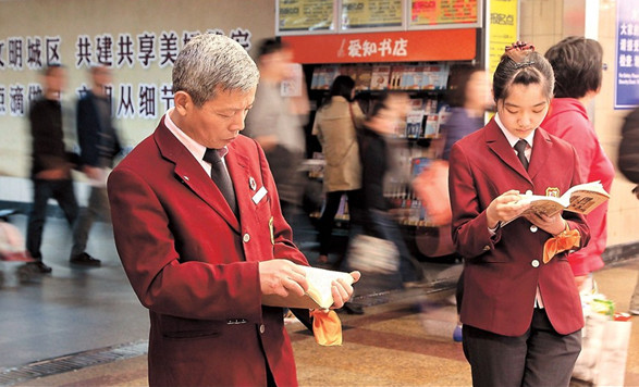 Subway staff take a break to read books during a flash mob event yesterday at Shanghai Metros Jiangsu Road Station to mark World Book Day. More than 30 volunteers joined the initiative at the Line 2 station, aimed at encouraging the public to spend more time reading books. — Dong Jun 