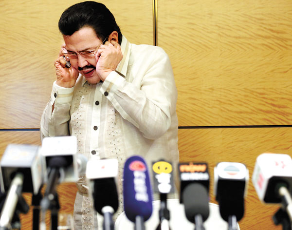 Joseph Estrada, mayor of Manila, tends to earpiece problems at a news conference in Hong Kong on Wednesday. Hong Kong and the Philippines have reached a consensus over a diplomatic row arising from a 2010 hijack incident. [Photo by EDMOND TANG/CHINA DAILY]