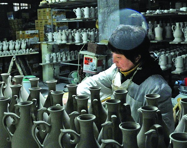 An artisan produces ceramic works in an old porcelain factory in Jingdezhen, Jiangxi province. [Photo by Zhang Wu / Xinhua]