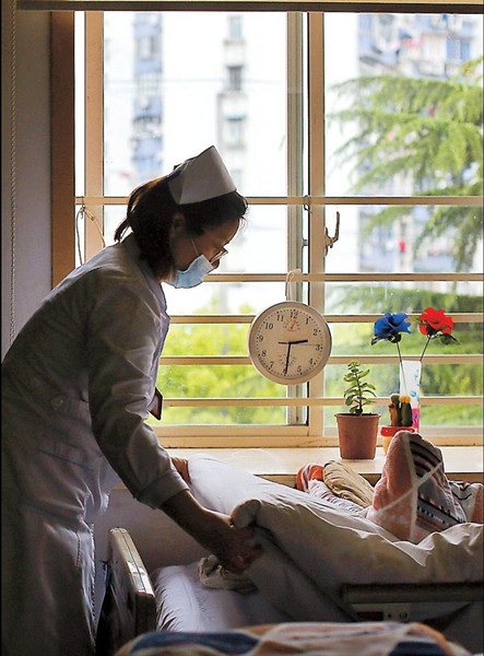 A nurse makes a bed at a palliative care center in a community in Zhabei District. — Wang Chen
