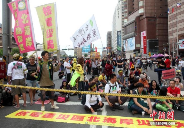 Thousands of people occupy the Zhongxiao West Road, a busy street in front of the train station in Taipei on Sunday afternoon. They sat or lied down on the ground to protest the construction of the island's fourth nuclear power plant. [Photo/Chinanews.com]