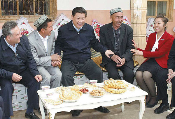 President Xi Jinping has a chat with Abudulkeyoum Rozi (to his right) and his family members at the villager's home in Kashgar, the Xinjiang Uygur autonomous region, on Monday. Photo by Xinhua