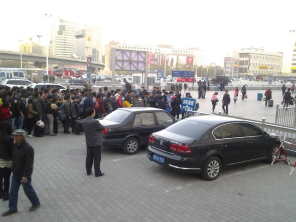 People wait at an entrance to the south railway station of Urumqi, capital of northwest China's Xinjiang Uygur Autonomous Region, after an explosion on April 30. People in the square in front of the station and nearby were evacuated immediately after the blast, and police cordoned off all entrances to the square of the station. [Photo by Gao Bo/China Daily]