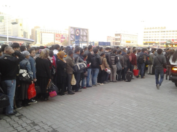 People wait at an entrance to the south railway station of Urumqi, capital of northwest China's Xinjiang Uygur Autonomous Region, after an explosion on April 30. People in the square in front of the station and nearby were evacuated immediately after the blast, and police cordoned off all entrances to the square of the station. [Photo by Gao Bo/China Daily]