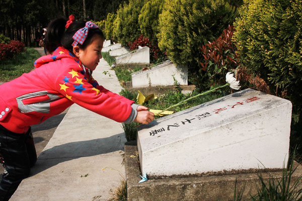 A girl places a flower on the gravestone of a Chinese soldier.