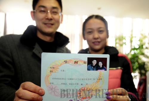 ELIGIBLE COUPLE: He Shaodong and wife Zhou Jun, residents in Hefei City, Anhui province, show their permit that allows the couple to have a second child, on February 14. Zhou is the only child in her family (LIU JUNXI)