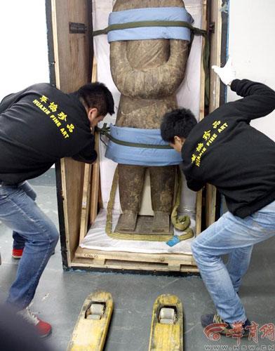 Employees move a statue from the shipping container which requires great skill. [Photo/hsw.cn]