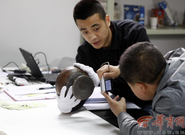 An employee takes picture of a relic and makes a record of it. [Photo/hsw.cn]