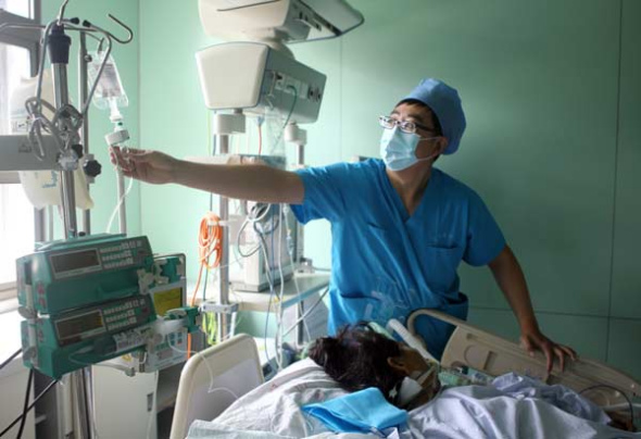 Xue Lei treats a patient at the intensive care unit at Peking University Third Hospital. [Photo by Zou Hong / China Daily]