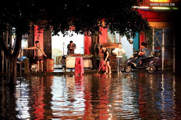 People cleans off water on a flooded road in Liuzhou City, south China's Guangxi Zhuang Autonomous Region, May 10, 2014. Northeastern part of Guangxi was hit by a rainstorm at night of May 9 and local government has launched an emergency response. (Xinhua/Deng Liting)