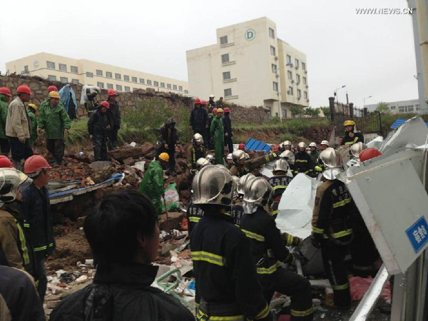 Photo taken by a mobile phone shows rescuers working at the accident site in Huangdao Island, east China's Shandong Province, May 11, 2014. Eighteen people were killed and another three injured early Sunday morning after a rainstorm-triggered wall collapsed here, said local authorities. (Xinhua)