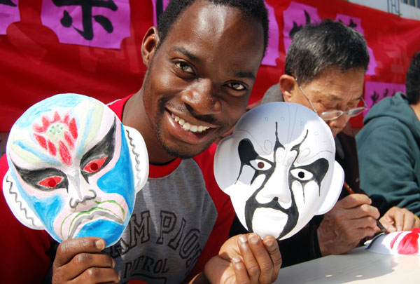 Osei Boateng, a Ghanaian student at Jiangsu University who is learning Chinese, shows Peking opera masks during a visit to a community theater in Zhenjiang, Jiangsu province, in March. Shi Yu Cheng / for China Daily