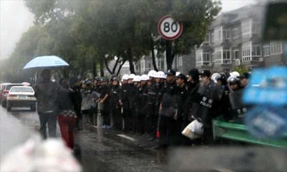 Police officers stand on alert at an entrance of Jiufeng village in Hangzhou, Zhejiang province on Sunday afternoon. Clashes broke out Saturday after thousands of protesters rallied against a planned garbage incinerator in the village. [Photo: Yang Hui/GT]