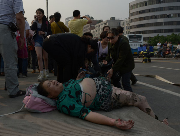 An injured woman lies on a road after a bus explosion killed one man and injured at least 24 people in Yibin, Sichuan province, May 12. [Photo provided to China Daily]