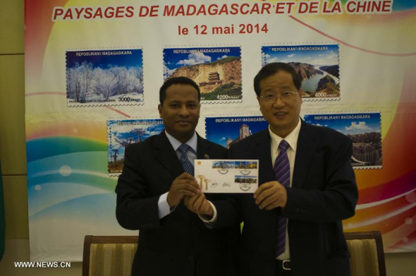 Madagascar's Minister of Posts, Telecommunications and New Technologies Andre Neypatraike (L) and Chinese Ambassador to Madagascar Yang Min issue postage stamps containing landscapes of Madagascar and China in Antananarivo on May 12, 2014. (Xinhua/He Xianfeng)