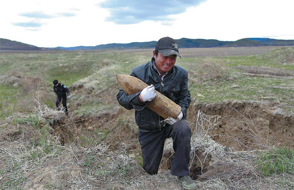 Ding Haibo from Xingfa village in Dunhua city, Jilin province, carries a discarded shell he found in a field. [Photo by Feng Yongbin/China Daily]