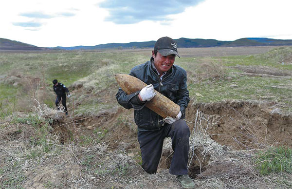 Ding Haibo from Xingfa village in Dunhua city, Jilin province, carries a discarded shell he found in a field. [Photo by Feng Yongbin/China Daily]