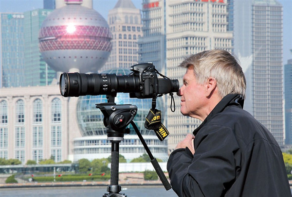 A foreigner takes photographs at the Bund but visitor numbers are down. — Zhang Suoqing 