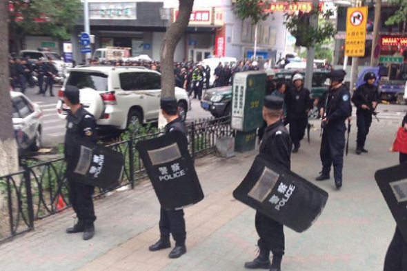 Police officers stand guard near a blast scene, which has been cordoned off, in downtown Urumqi, capital of northwest China's Xinjiang Uygur Autonomous Region, May 22, 2014. (Xinhua/Cao Zhiheng)