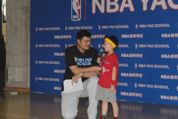 Chinese basketball legend Yao Ming talks with a student from the NBA Yao School at the graduation ceremony of the first-phase of the program at the Wukesong Hi-Park in Beijing, May 24. [Photo by Yan Weijue/chinadaily.com.cn]