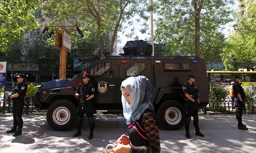 Police stand guard in a street in Urumqi, Xinjiang Uyghur Autonomous Region on Saturday as a local resident walks by. Security efforts were intensified after a terrorist attack occurred on Thursday at a market in the city, killing 43. Photo: Cui Meng/GT